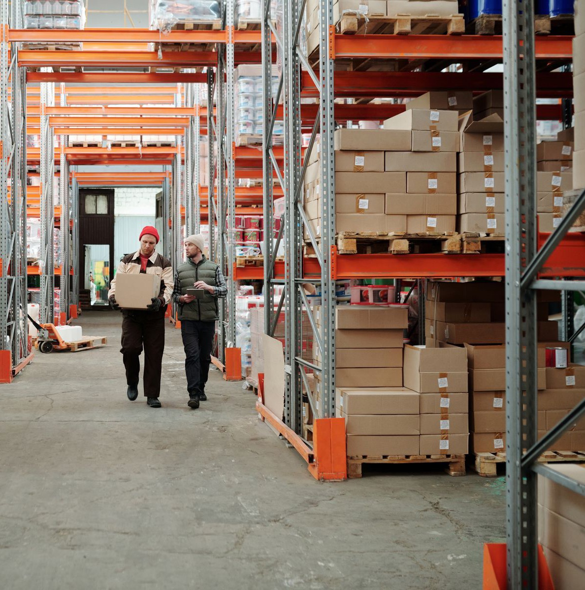 A warehouse aisle with workers moving plain cartons