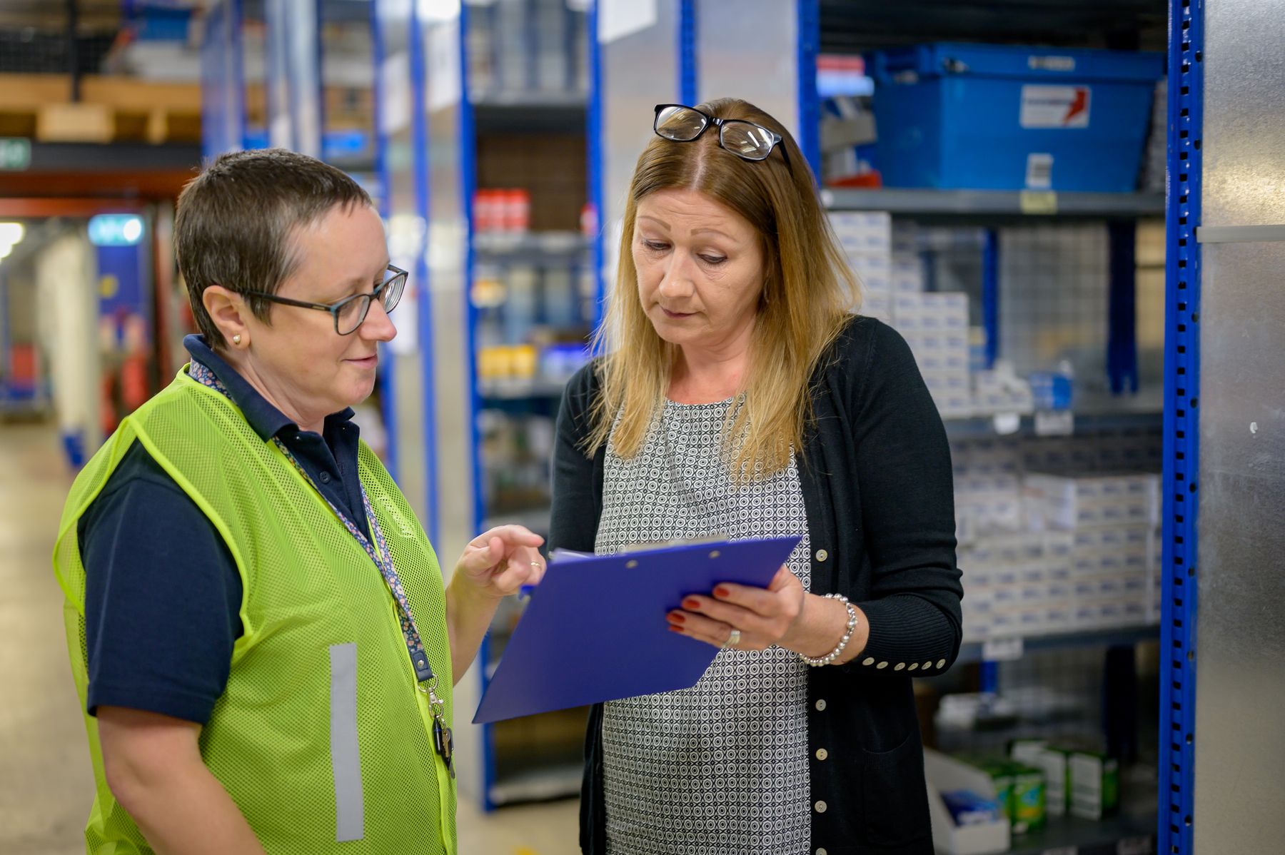 Two colleagues reviewing a clipboard in a stockroom
